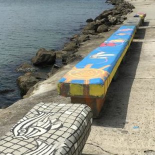 The stone benches along the shore display the delightful work of local artists.