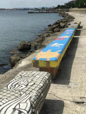 The stone benches along the shore display the delightful work of local artists.